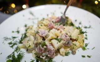 salade de noël russe traditionnelle olivier sur une assiette blanche. photo