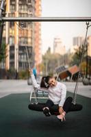 jeune femme monte sur une balançoire à l'aire de jeux. photo