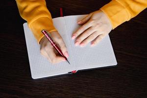 femme écrivant dans un cahier vierge. gros plan d'une main tenant un stylo. photo