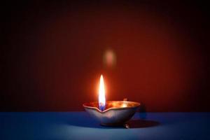 joyeux Diwali. symboles traditionnels du festival indien de la lumière. brûler des lampes à huile diya et des fleurs sur fond rouge. photo