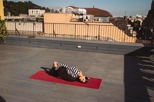 femme faisant des exercices de yoga sur le toit de la maison tôt le matin photo