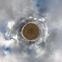 petite planète dans le ciel bleu avec de beaux nuages. transformation du panorama sphérique à 360 degrés. vue aérienne abstraite sphérique. courbure de l'espace. photo