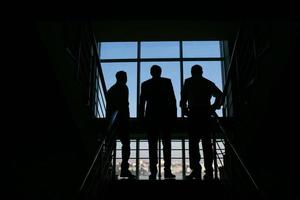 trois hommes d'affaires debout à la fenêtre avec vue sur la ville photo