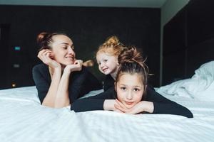 maman et ses deux filles s'amusent sur le lit photo
