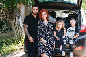 famille heureuse posant devant la caméra près de la voiture photo