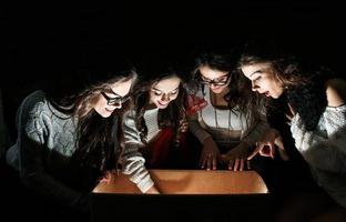 les soeurs ouvrent une boîte avec un cadeau de noël et des regards fascinés à l'intérieur photo