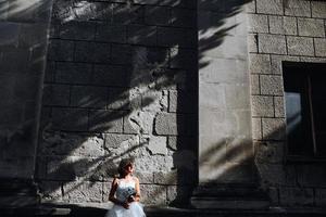 mariée posant sur fond de mur de pierre photo