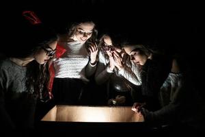 les soeurs ouvrent une boîte avec un cadeau de noël et des regards fascinés à l'intérieur photo