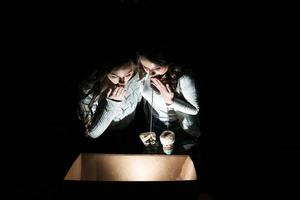 les soeurs ouvrent une boîte avec un cadeau de noël et des regards fascinés à l'intérieur photo