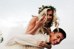 le marié porte la mariée sur son dos à l'extérieur photo