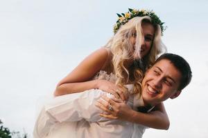 le marié porte la mariée sur son dos à l'extérieur photo