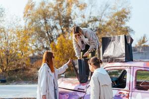 jeunes femmes posant près d'une vieille voiture décorée photo