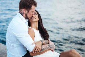 jeune couple est assis sur la jetée au bord de la mer photo