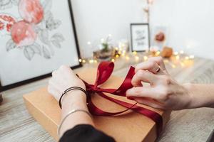 femme emballant présente dans du papier avec ruban rouge. photo