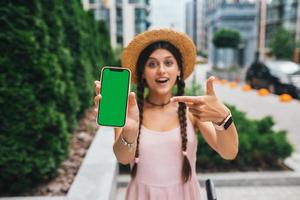 femme montrant un smartphone moderne avec écran vert pour le remplacement photo