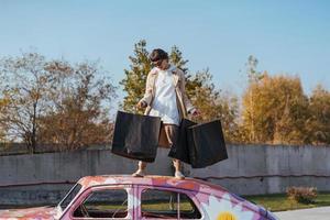 une jeune femme est debout dans une voiture avec des sacs dans les mains photo