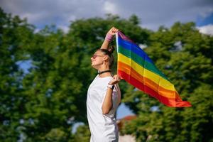 jeune femme agitant le drapeau de la fierté lgbt dans le parc. photo