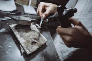 dans l'atelier, une bijoutière s'affaire à souder des bijoux photo