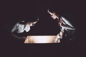 les soeurs ouvrent une boîte avec un cadeau de noël et des regards fascinés à l'intérieur photo