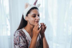 beau modèle appliquant un traitement de crème cosmétique sur son visage photo