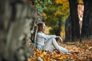 fille assise dans les feuilles d'automne photo