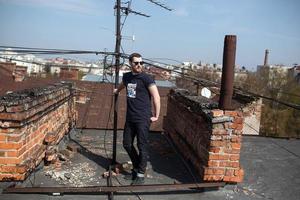 l'homme aux authentiques bottes et jeans lisière sur le toit de l'immeuble de la vieille ville photo