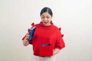 heureuse femme asiatique portant une chemise rouge avec une boîte-cadeau à portée de main pour le festival de noël photo