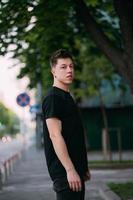 jeune homme adulte dans un t-shirt noir et un jean marche dans une rue de la ville photo
