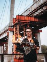 un gars lit un journal en feu, en arrière-plan un pont photo