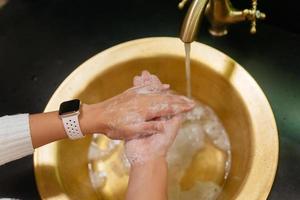 photo en gros plan d'une femme se lave les mains avec de l'eau et du savon.