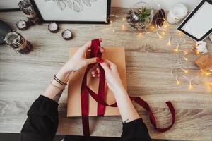 femme emballant présente dans du papier avec ruban rouge. photo