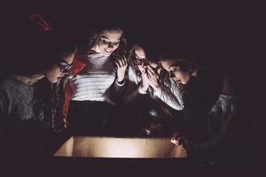 les soeurs ouvrent une boîte avec un cadeau de noël et des regards fascinés à l'intérieur photo