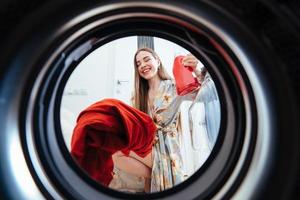 jeune femme à la maison met la robe dans la machine à sécher. photo