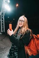 femme blonde avec smartphone la nuit dans la rue. photo