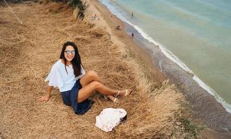 jolie femme en jupe et chemise d'été est assise sur le rivage photo
