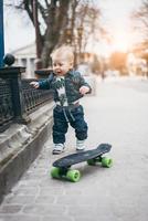 petit garçon drôle avec planche à roulettes dans la rue photo