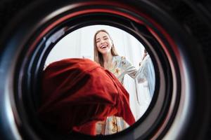 jeune femme à la maison met la robe dans la machine à sécher. photo