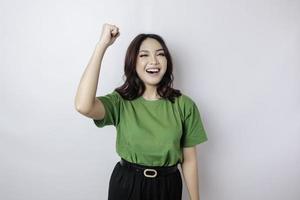 une jeune femme asiatique avec une expression heureuse et réussie portant une chemise verte isolée par fond blanc photo