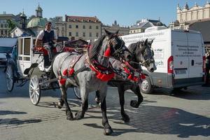 Cracovie, Pologne - 19 septembre. Calèche et chevaux parmi le trafic à Cracovie, Pologne le 19 septembre 2014. Trois personnes non identifiées photo