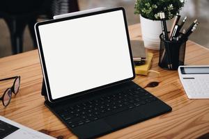 une tablette à écran blanc placée sur le bureau au travail. peut mettre du texte ou des médias dans la zone sur l'écran blanc. photo