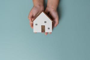 mains d'enfant tenant une petite maison en bois, concept de vie. photo