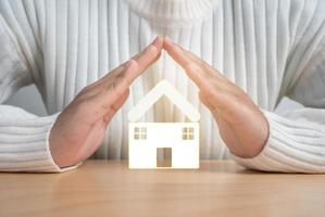 mains protégeant le concept de petite maison en bois de protection ou d'épargne pour un nouveau projet résidentiel.
