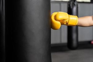 sac de boxe portant des gants de boxe jaunes. copie espace photo