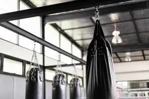 de nombreux sacs de sable noirs pour boxeur dans la salle de gym. photo