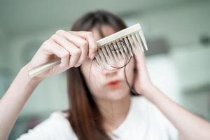 une femme asiatique a un problème avec la perte de cheveux longs attachée à la brosse à peigne. photo