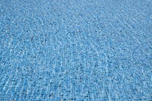 le vent fait onduler l'eau. arrière-plan abstrait de l'eau de surface claire. piscine bleue reflétant les ondulations du soleil. motif du fond de la piscine en carreaux bleus en céramique mosaïque ondulée. photo