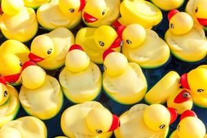 de nombreux canards jouets jaunes en caoutchouc flottant dans la piscine pour enfants se bouchent. photo