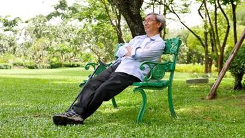 heureux homme asiatique assis sur un banc dans le parc. photo