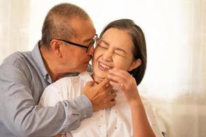 mari asiatique s'embrassant sur la joue de sa femme. photo