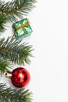 vue de dessus des boules rouges de boîte-cadeau de noël avec des branches d'épinette, des pommes de pin, des baies rouges et une cloche sur fond blanc. photo